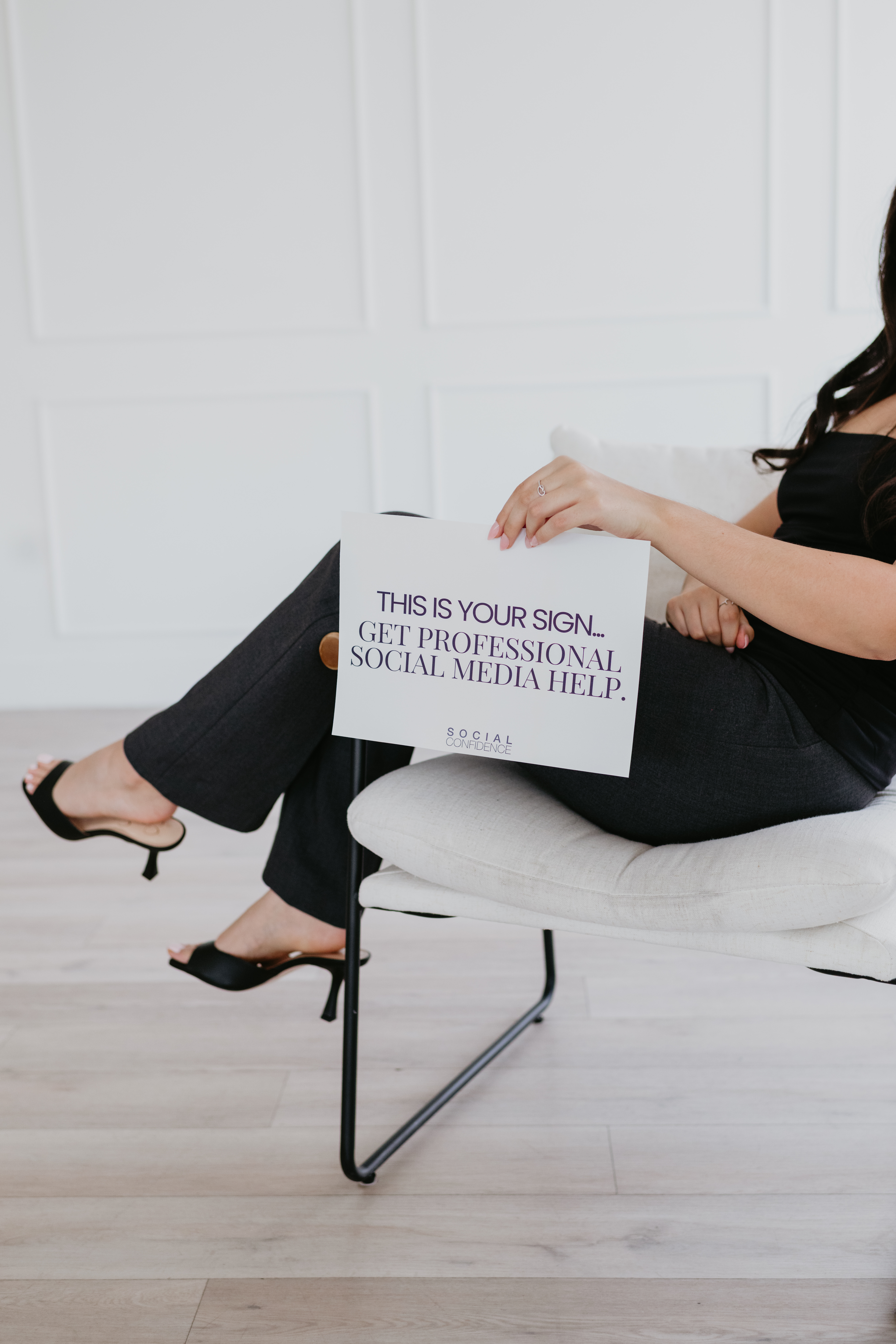 Client seated with a sign reading: this is your sign, get professional social media help
